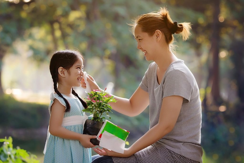 Kid holding a plant with her mom